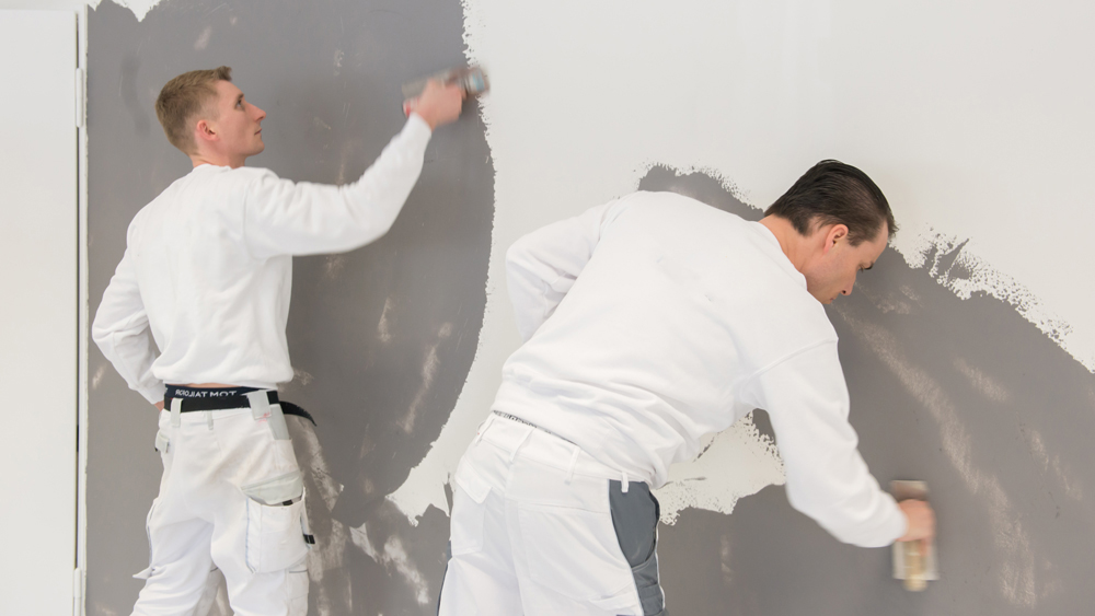 Zwei Maler beim Verputzen von Wänden