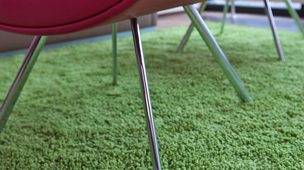 Roter Couchsessel auf grünem Teppich